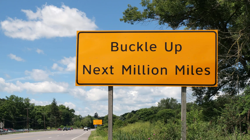 "Buckle up next million miles" road sign