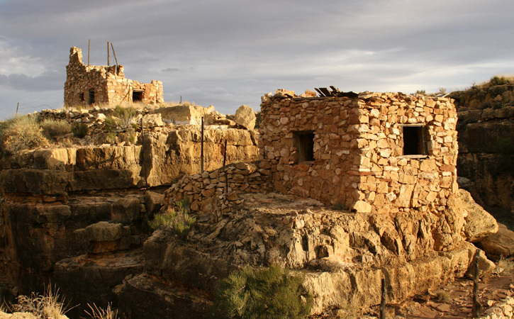 Stone ruins at Apache Death Cave stand alone and silent against a cloudy sky.