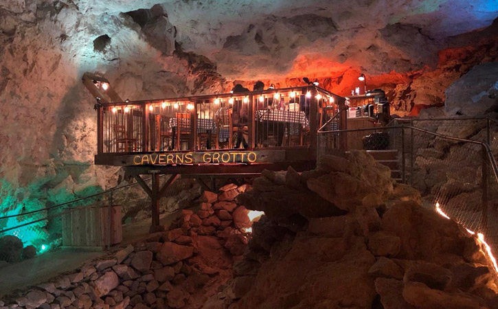 In a cave, a small deck built has been built with tables arranged for dining.