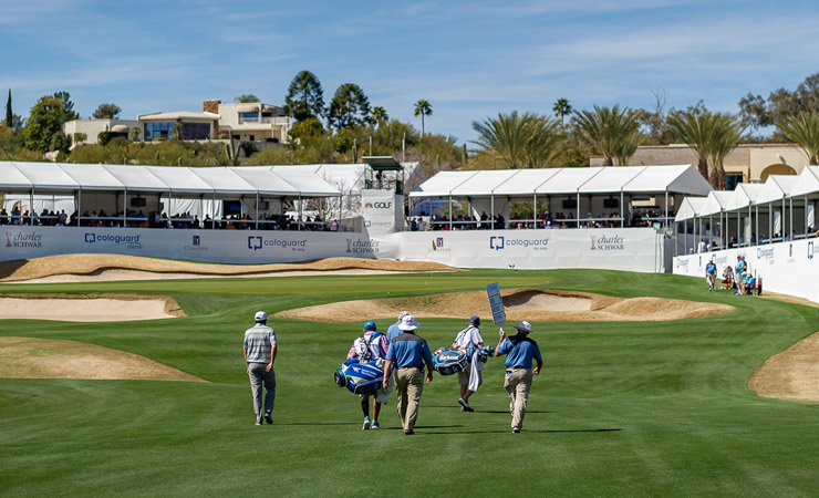 A group of men in golf clothes walk to the next hole on a golf course