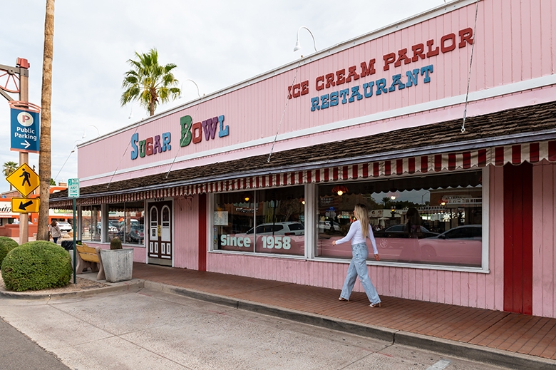 Julie walking into pink Sugar Bowl ice cream shop building.