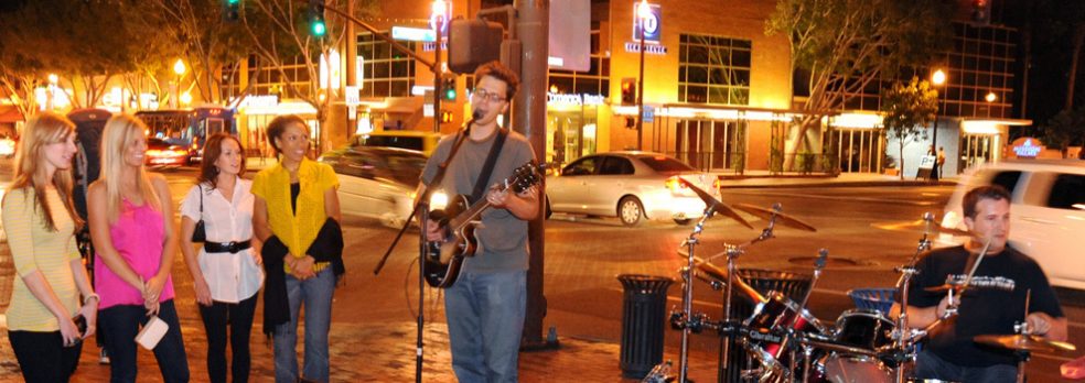 Four women look on as two musicians play to the crowd on Mill Ave. in Tempe, Arizona