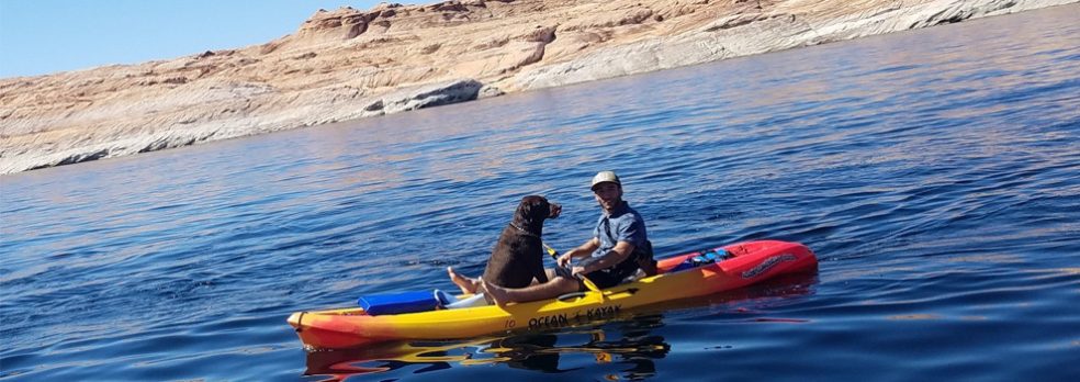 A man kayaks on Lake Powell with his dog.