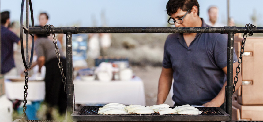 A diner waits to grab his food from a grill at a Cloth and Flame dinner.