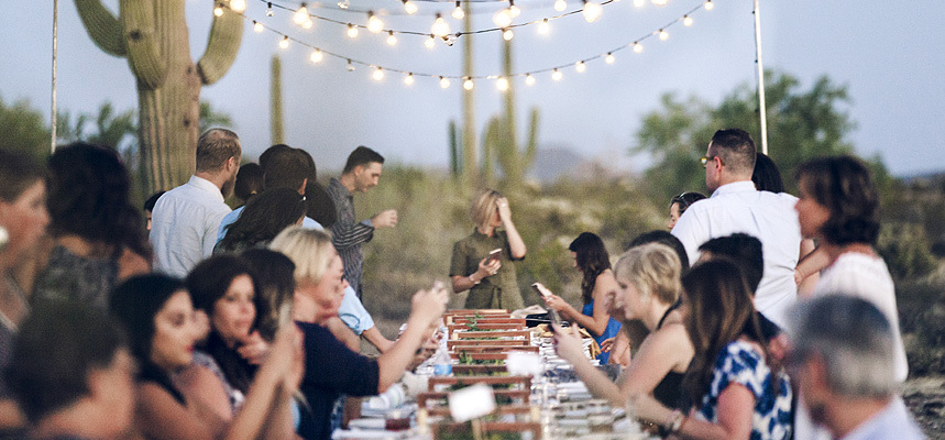 Diners sit and stand around a table before starting dinner.