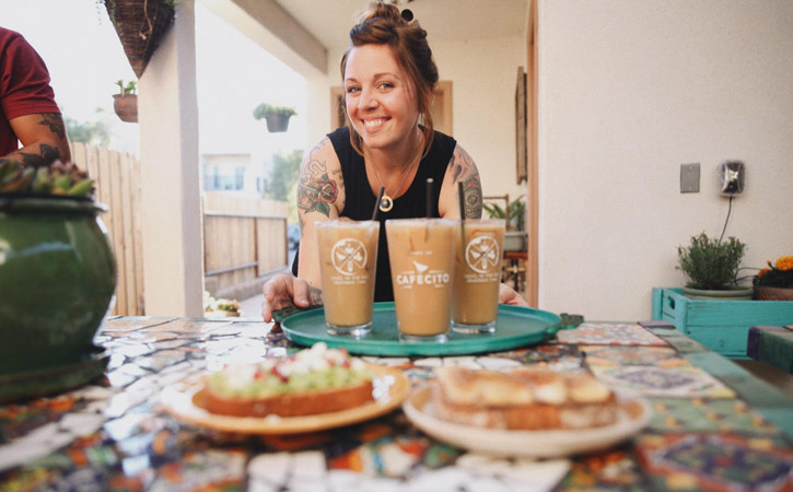 A woman holds a tray of several coffee drinks