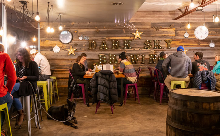 People sitting at tables, chatting and drinking inside Dark Sky Brewery in Flagstaff