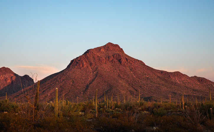 A single mountain peak rises in the air, lit by a setting sun