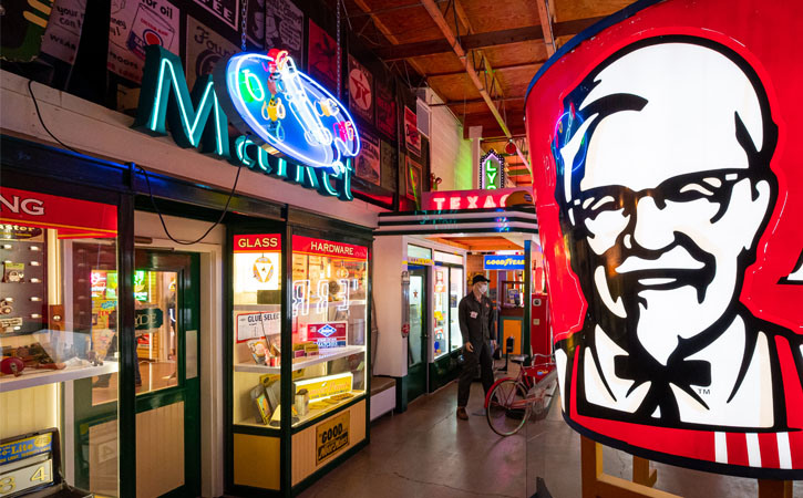 Large neon signs, the largest being a KFC bucket, decorate an exhibit of vintage art and advertising from America's past