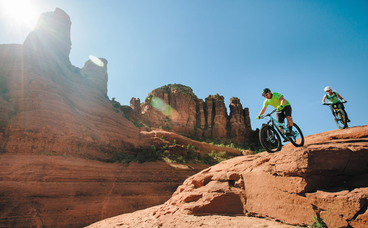 Two cyclists ride downhill on a Sedona mountain biking trail