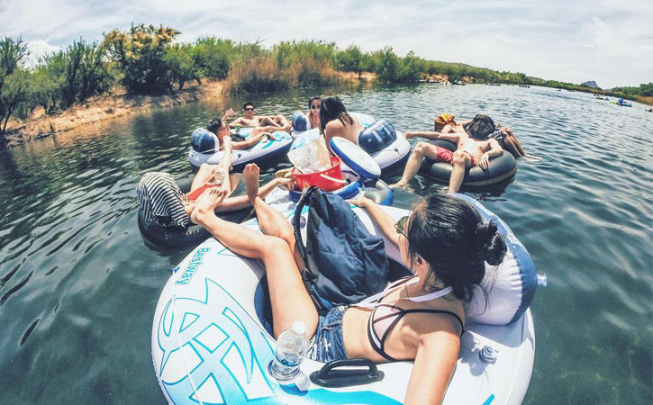 A group of friends hang out on the water in inner tubes.