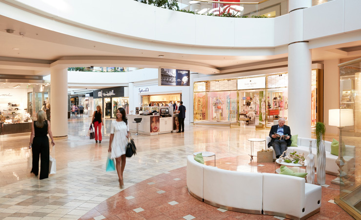 Shoppers walk through a bright and airy shopping mall