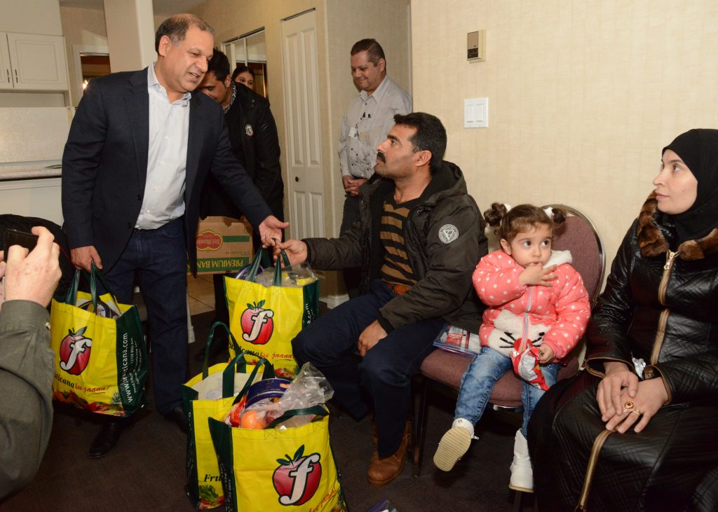 Tony Singh gives the first bags of groceries to Syrian family. Photos by Ray Hudson