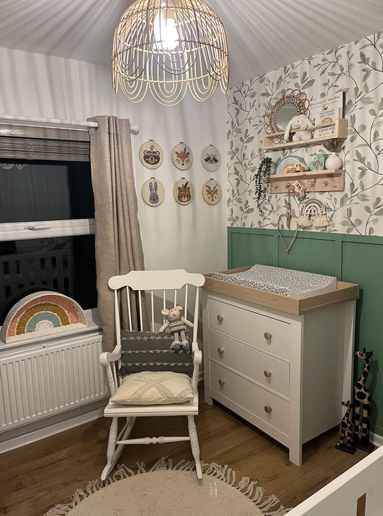 Gender neutral baby nursery with leafy wallpaper.