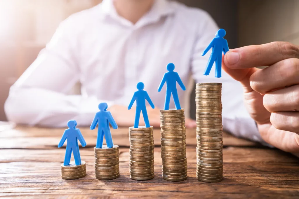 person placing toy people on stacks of coins