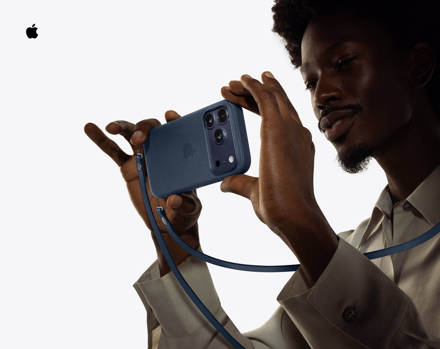 Person holding Phone 17 Pro to take a horizonal photograph, Deep Blue color, with Crossbody Strap around their shoulder