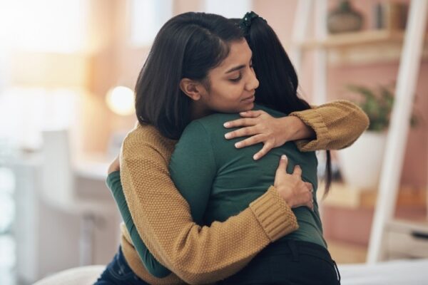 South asian woman embracing distressed friend