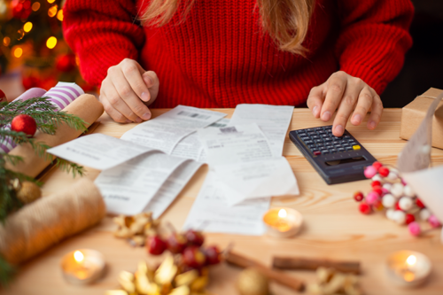 Image of a red sweatered young woman adding up her holiday gift bills