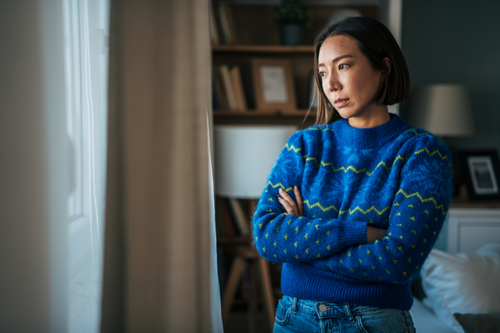 Young Asian Woman in a blue sweater looking pensive and feeling sad
