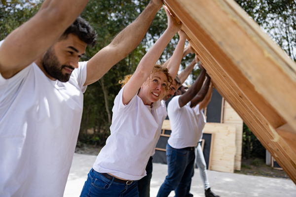 Image of a group of community volunteers raising a wood framed wall