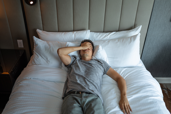 Frustrated man lying in bed struggling to sleep