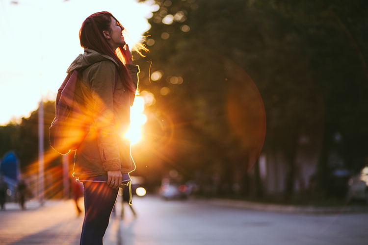 Female Walking In Sunlight With Smile On Her Face