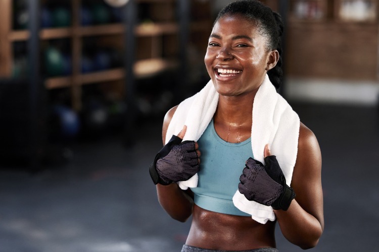 Happy sporty young black woman smiling as she meets her gym resolutions