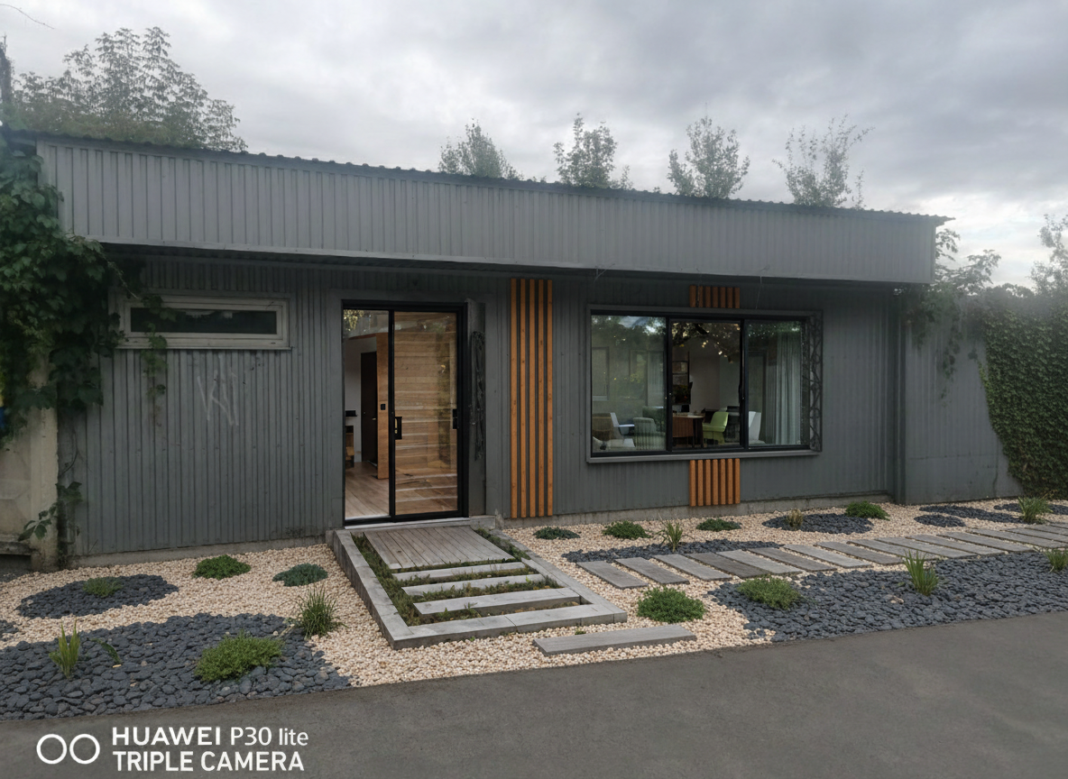 After - exterior transformation: Design type: exterior. Style Ref: https://base44.app/api/apps/68a6b71b9e6d8b9bb330a7ee/files/public/68a6b71b9e6d8b9bb330a7ee/45f6417ef_luwai_HD_1758484370326.png. Instructions: make a visualization of the facade in a modern style.
the facade should be gray in color and decorated with decorative wooden slats. make the landscape with decorative natural materials