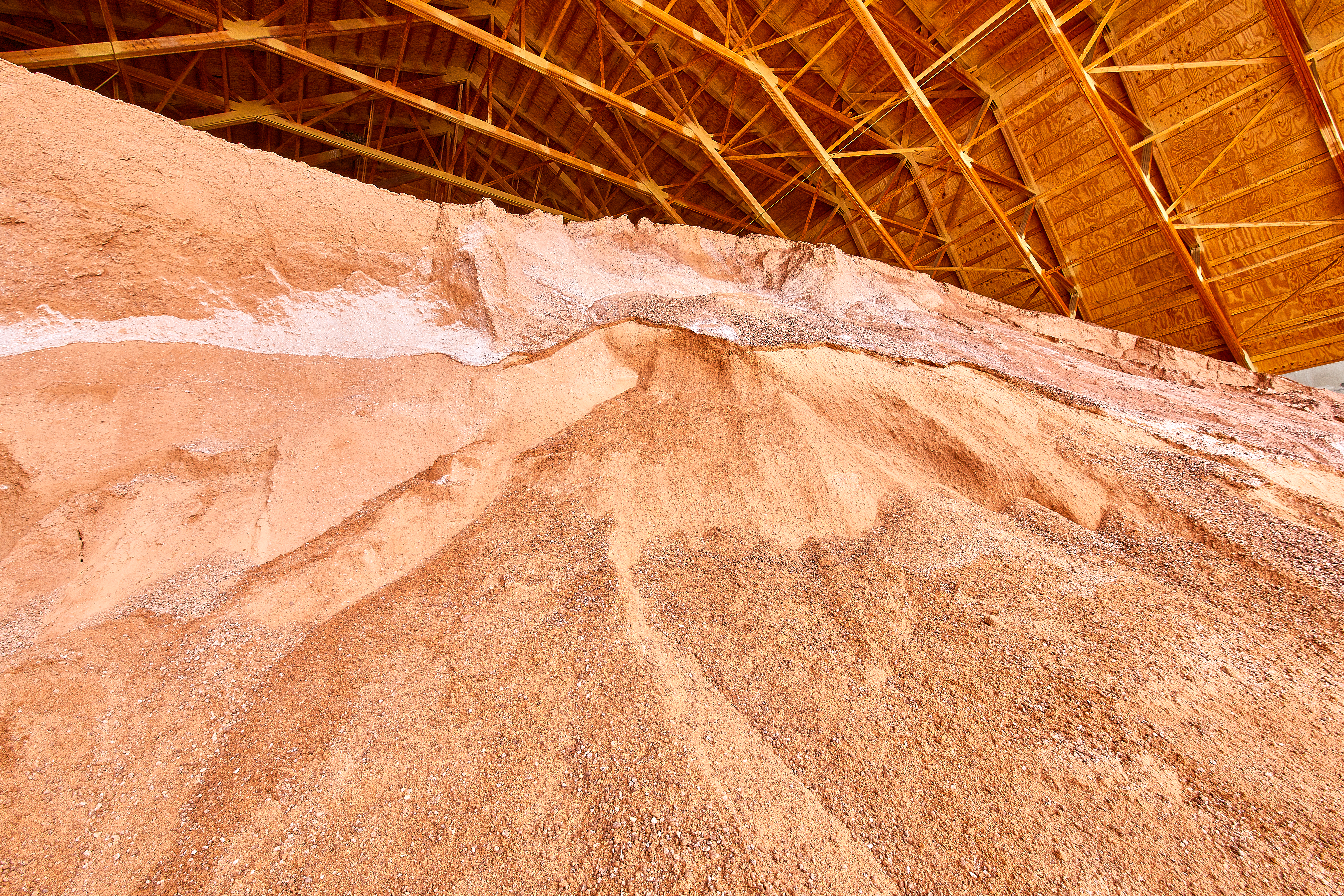 Red-hued salt is piled high in the solid de-icer material barn at the Public Works Operations Center.