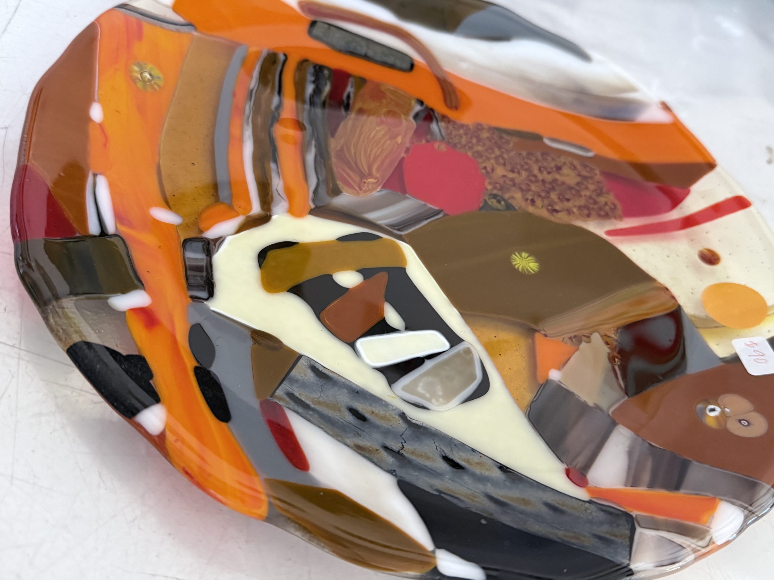 Fused glass plate featuring rich autumn tones of amber, orange, brown, cream, and black with intricate layered patterns that capture the warmth and movement of fall.