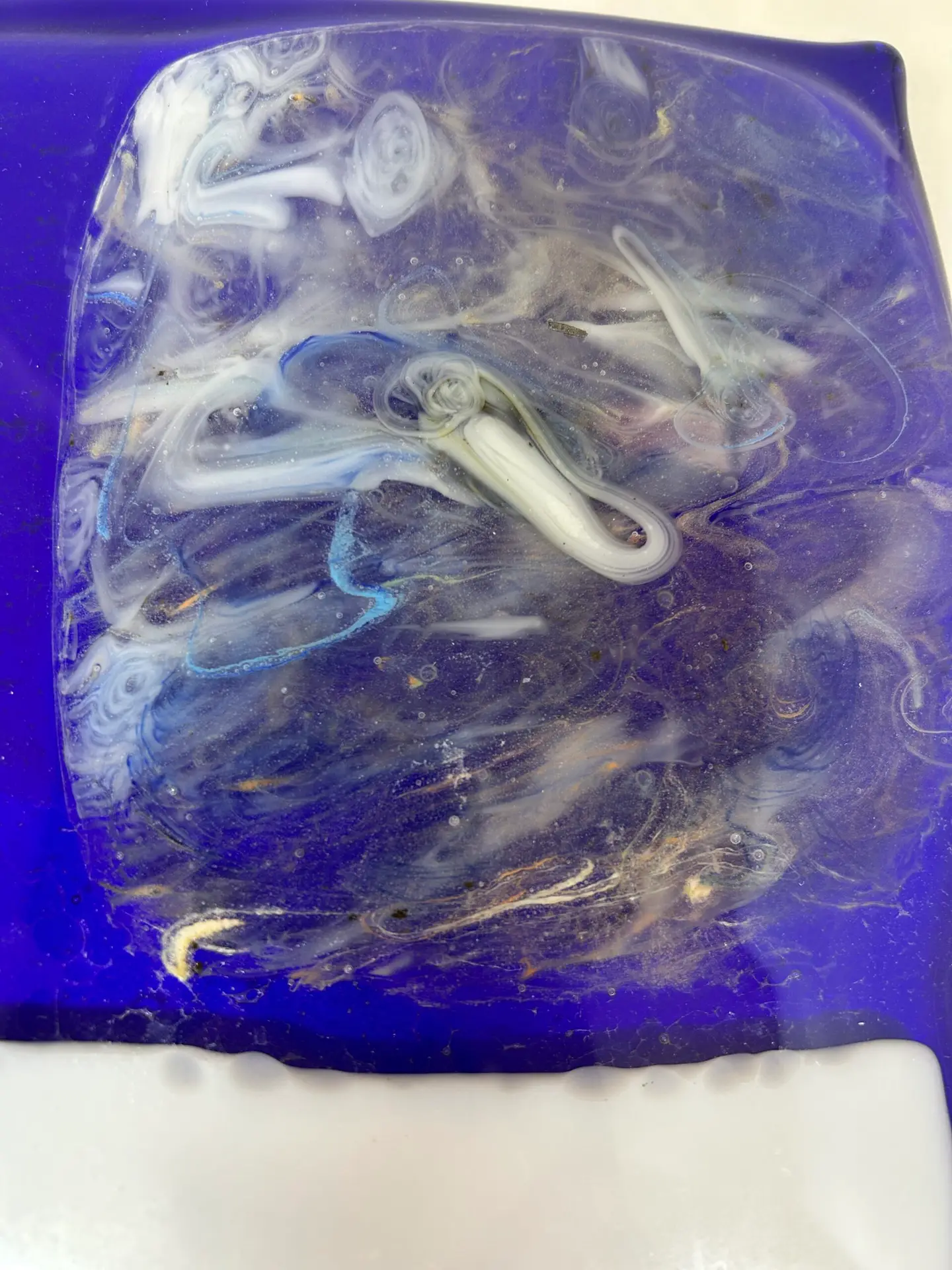 A close-up of a glass surface from Cosmic Drift, showcasing swirling white and blue patterns.