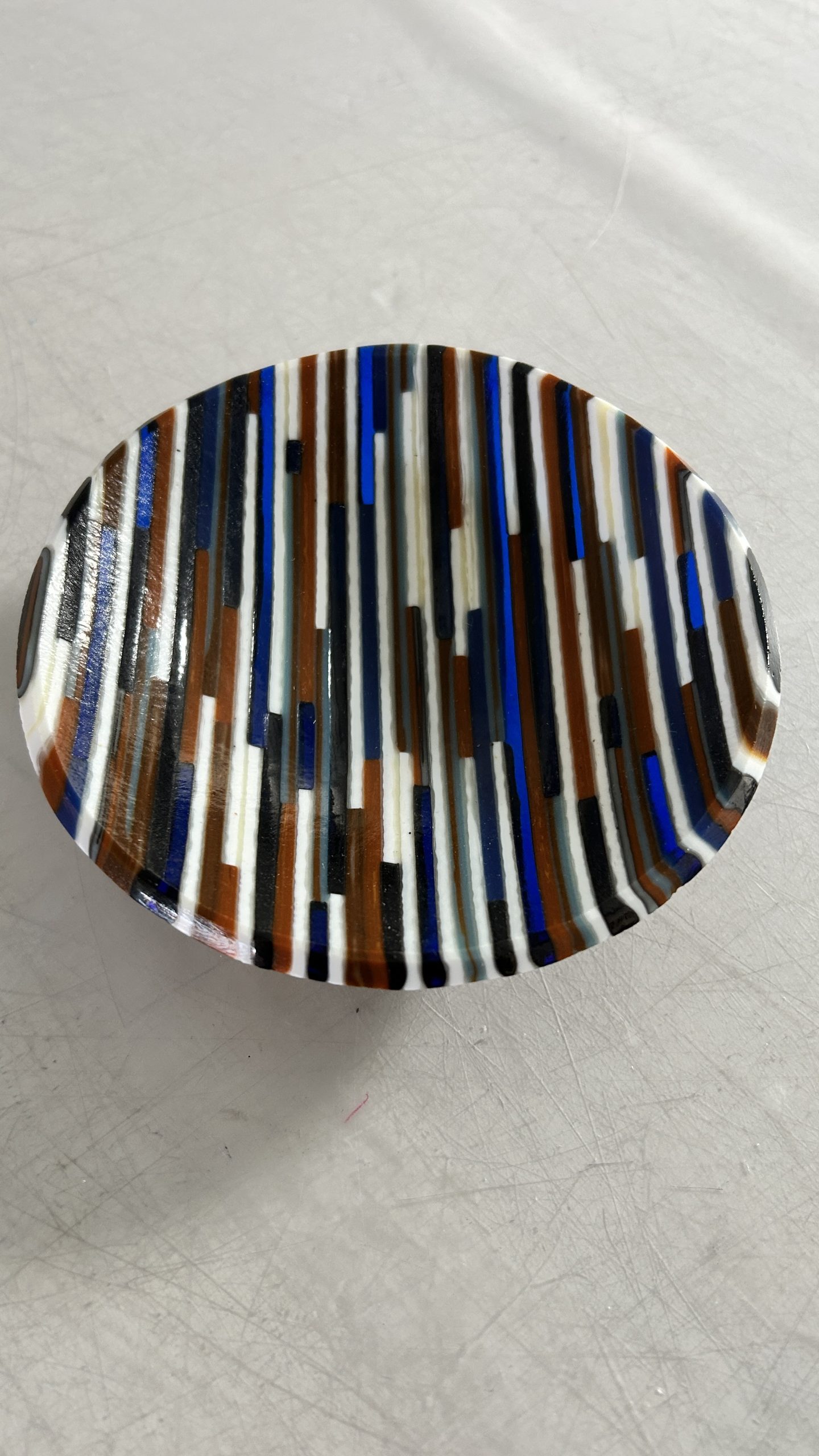 Strips of earthtone colored glass cut and assembled into a small bowl.