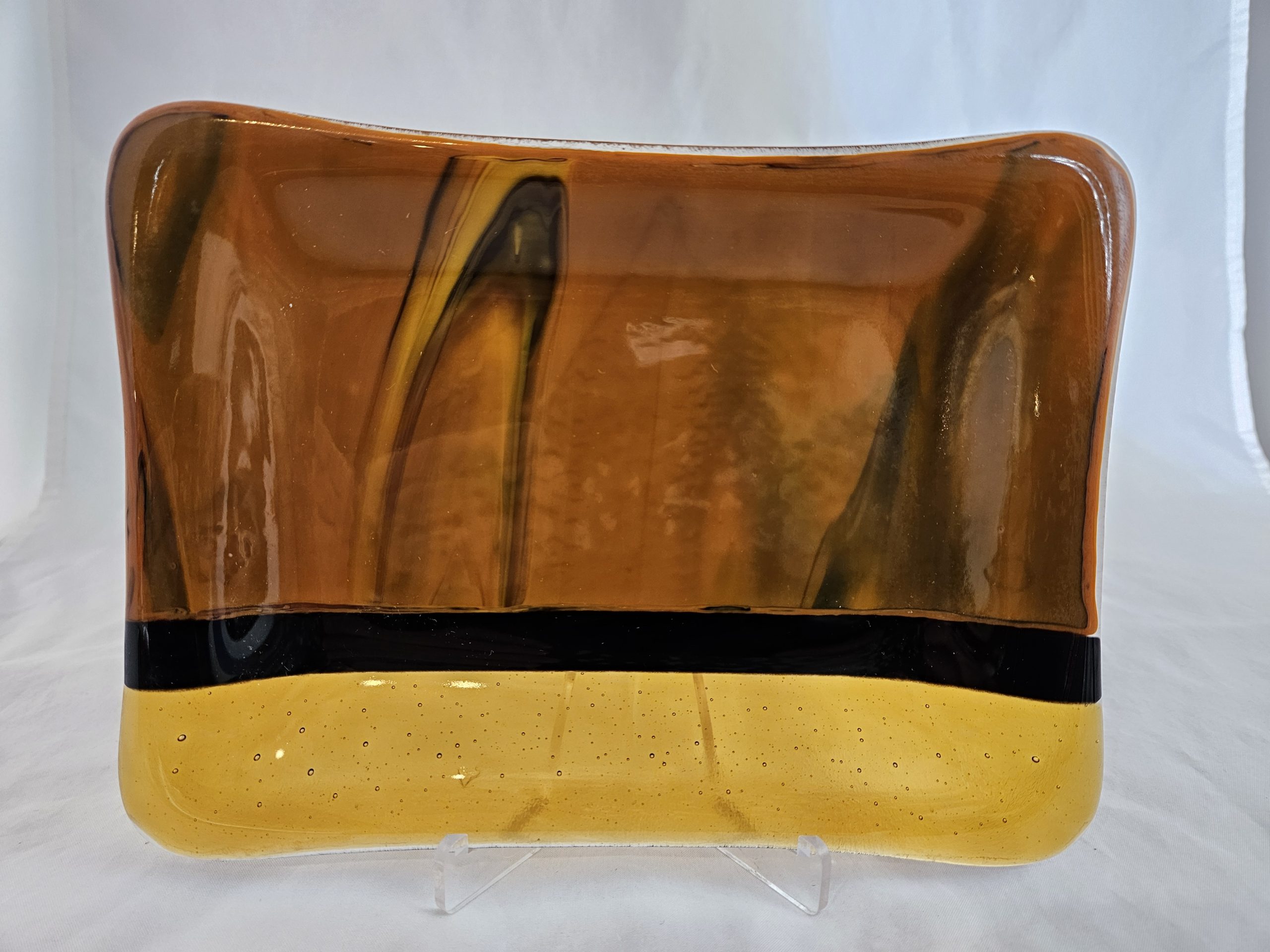 One-of-a-kind fused glass plate with glowing amber tones at Glass Arts Collective