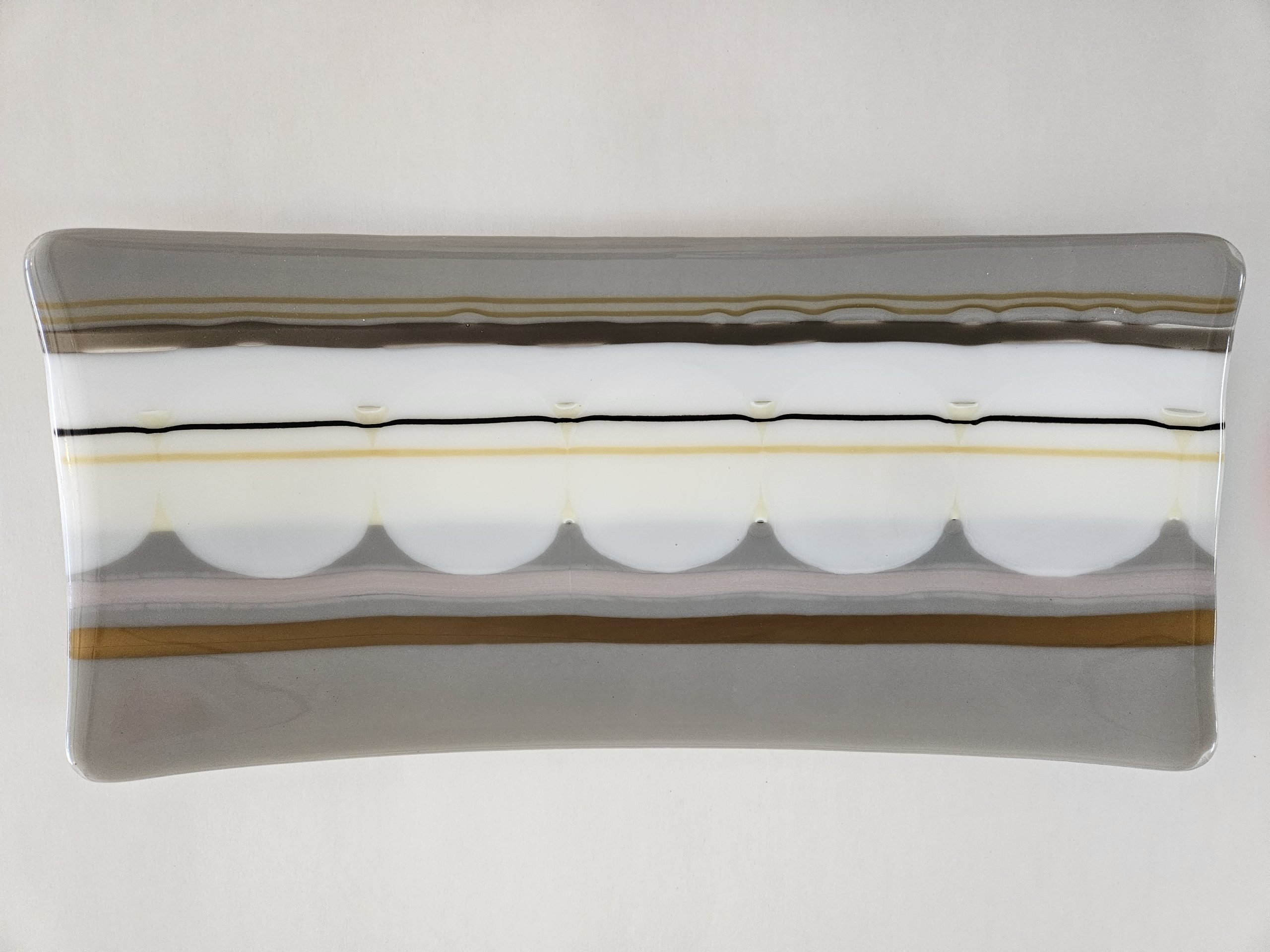 Modern fused glass tray with layered neutral tones by Carl Turnbull featuing gray, cream amber and black linear design