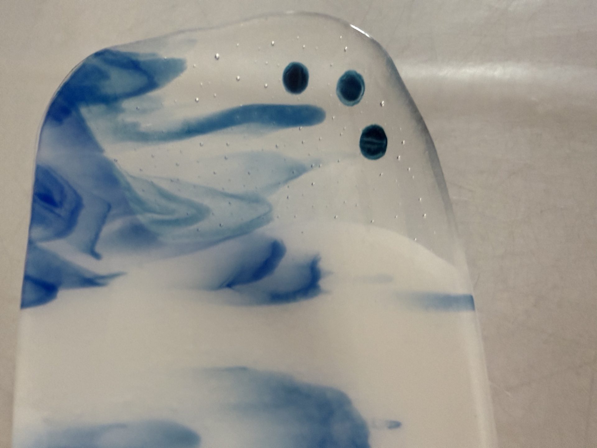 Fused glass with blue and white swirled with button accents on either side. By Nancy Dillingham Marks