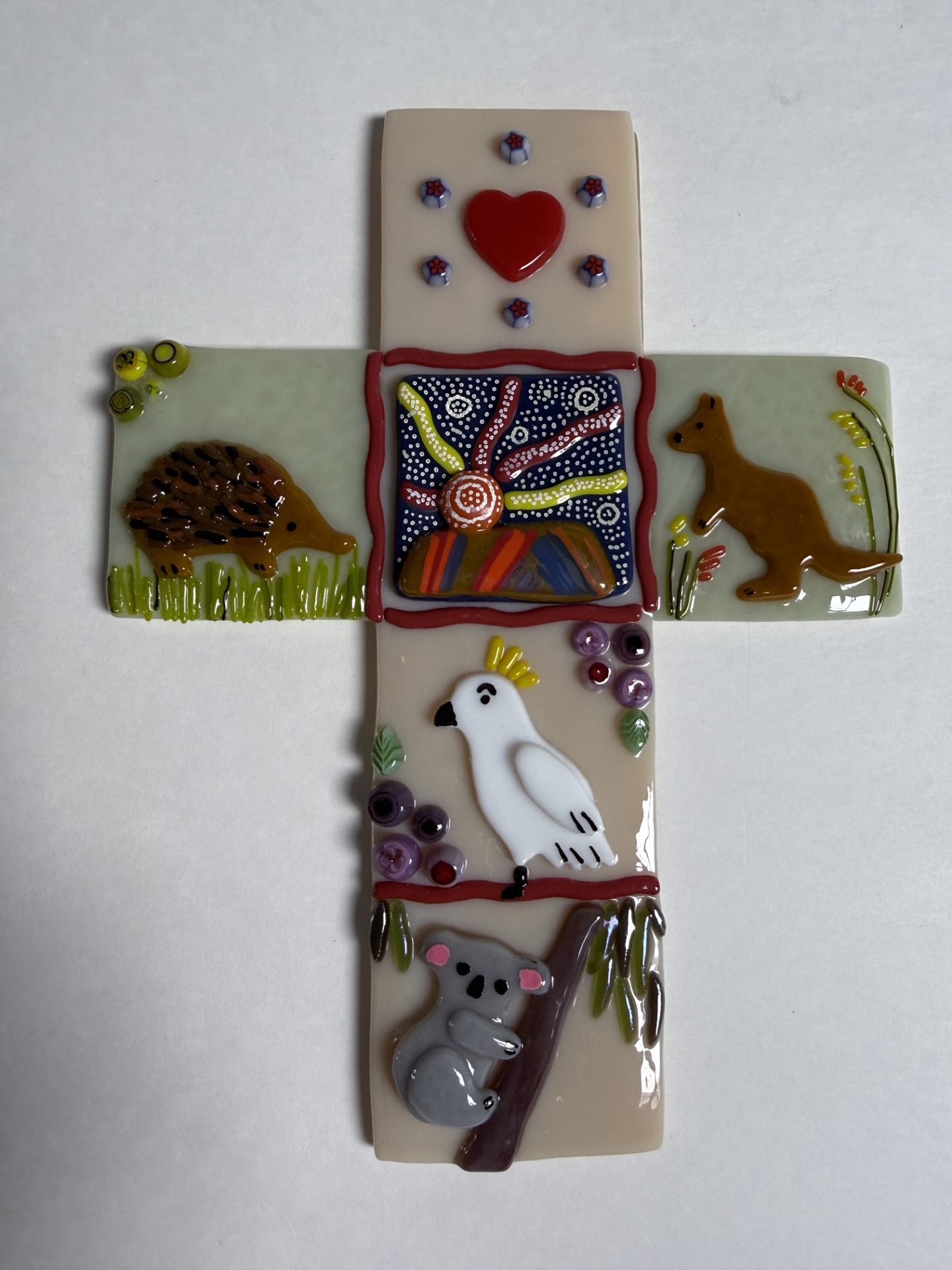 Fused glass Baptism Cross - Echidnas, Koala Bear, Uluru (formerly red rocks) Kangaroo and Kangaroo Paws flowers, Cocktoo, and a heart that is on all of the families custom made crosses.