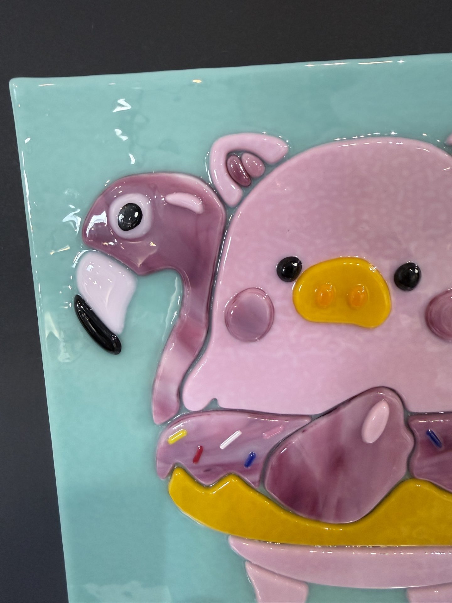 Lulu the Pig fused glass commission detail with flamingo and aqua background