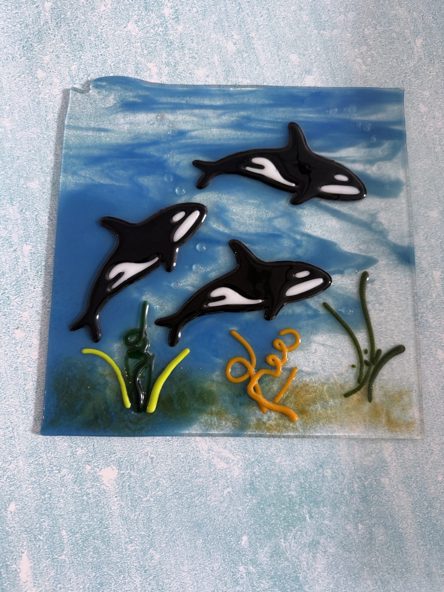 Square fused glass ocean artwork with three orcas, sea plants, coral, and bubbles