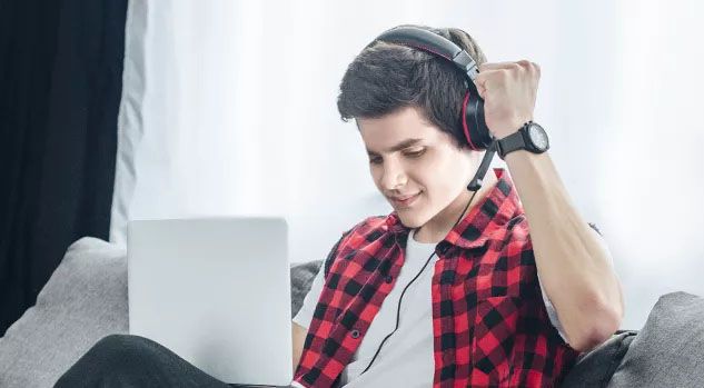 boy in red checker shirt with headphones on and arm raised