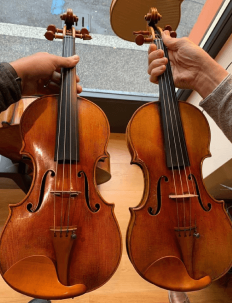 Person holding two violins copies handcrafted by Luiz Amorim