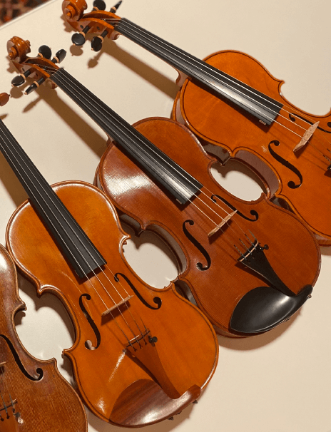 three handmade violins on a table