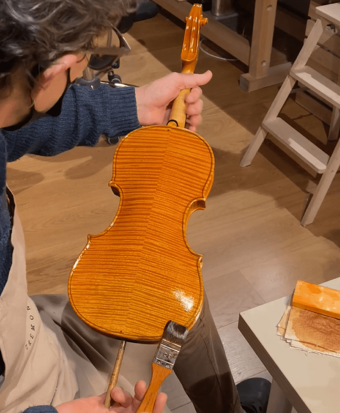 Luthier varnishing a violin at his workshop