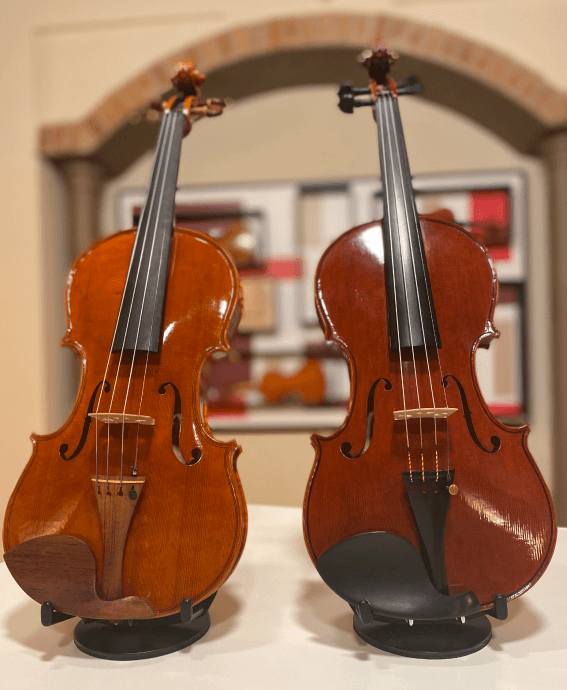 Two handmade violins standing together at Mio Cannone Violini Shop
