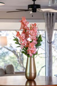 Coral-colored Gladiolus cut flower arrangement in a vase in front of a window