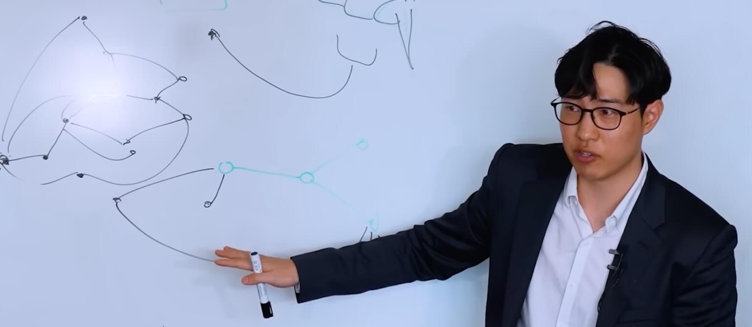 A man stands in front of a blackboard with a lot of digital patterns.