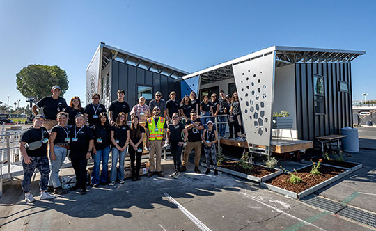 Engineering students in front of a sustainable home they built