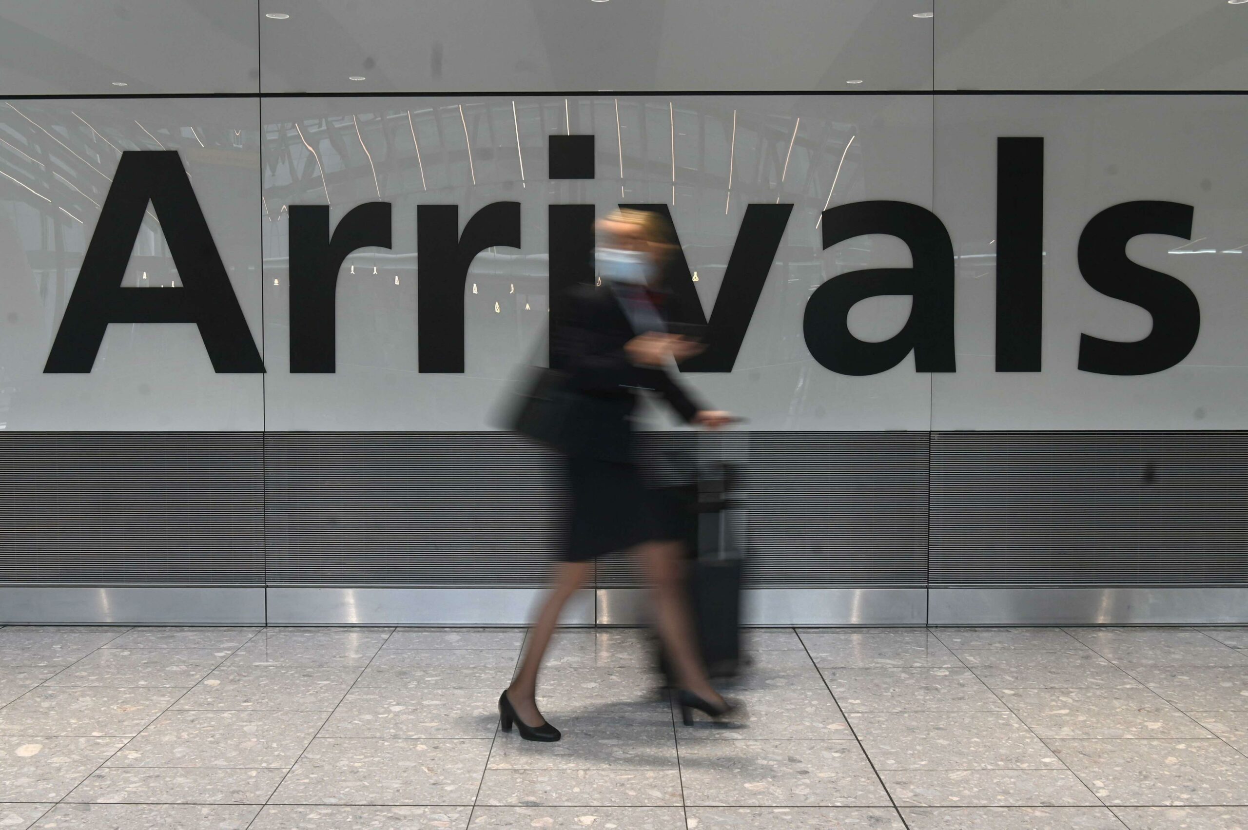 A passenger pulls her roller suitcase on arrival in Terminal 5 at Heathrow airport in London, England.