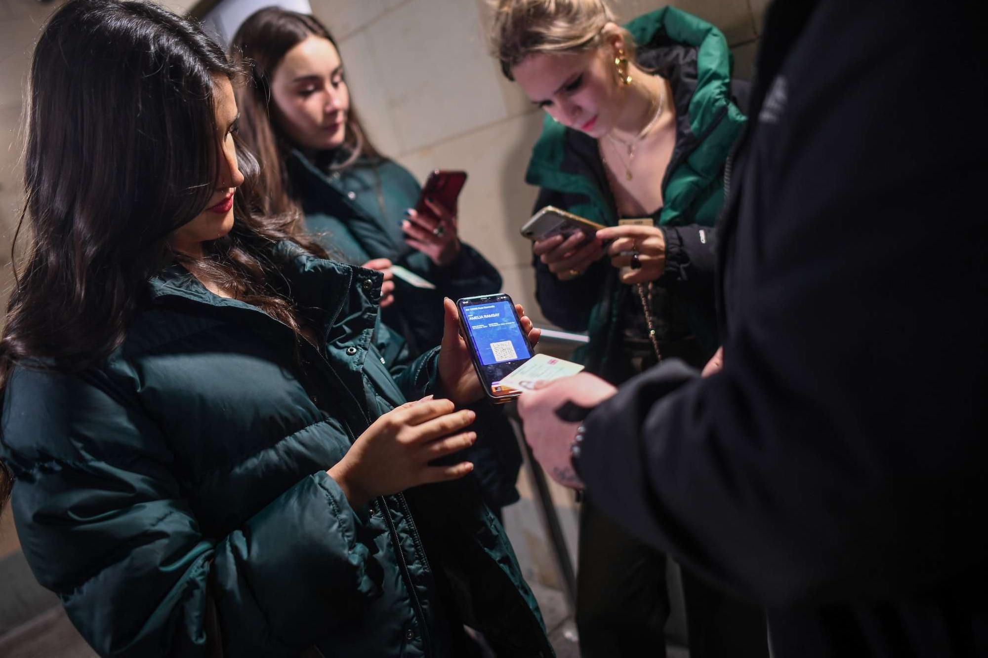 A group of women show their COVID passports as they enter La Belle Angele nightclub in Edinburgh, Scotland. The Scottish government's vaccine passport scheme came into effect in October, later negative tests were also allowed.