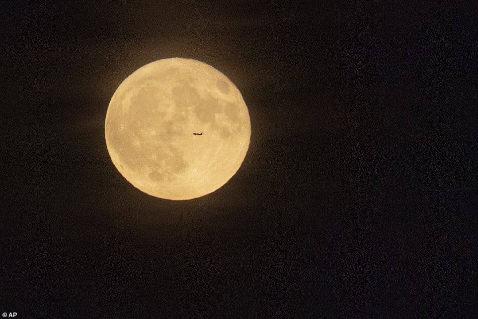 Un avión vuela frente a una luna que acaba de comenzar a desvanecerse de estar llena, mientras se eleva en Halloween, el sábado 31 de octubre de 2020, cerca de Graham, Washington DC