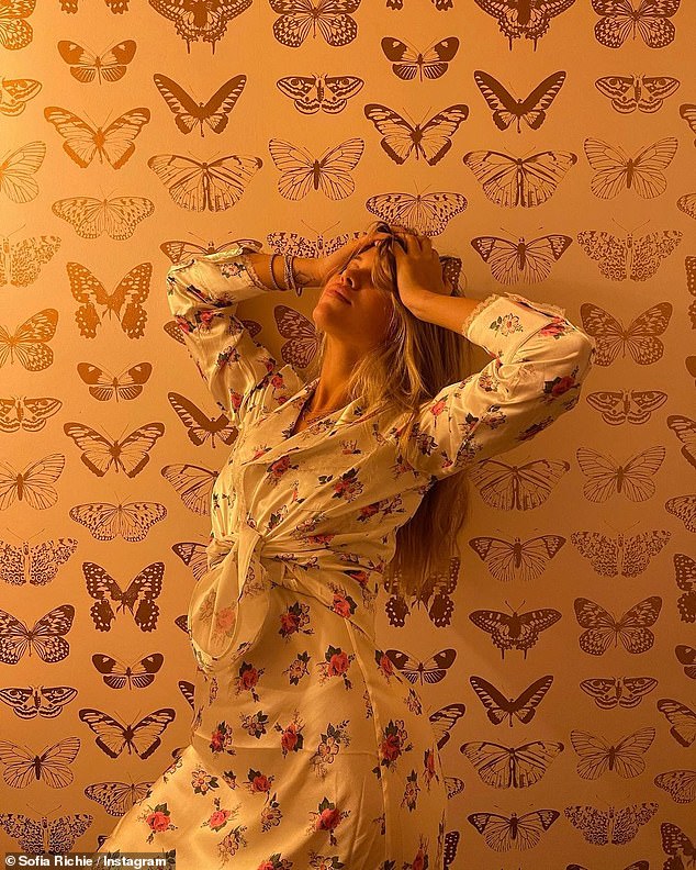 Flores y mariposas: Sofia Richie publicó un dúo de fotos encantadoras de sí misma en su cuenta de Instagram el lunes por la noche, con un vestido blanco de seda floral envuelto contra un fondo de pantalla de mariposas.